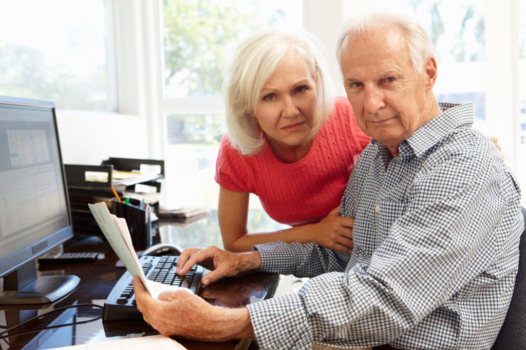Senior man and woman using computer at home
